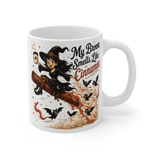 Funny witch riding a giant cinnamon stick with the quote "My Broom Smells Like Cinnamon" on an 11oz ceramic coffee mug featuring bats, whipped cream clouds, and cozy autumn artwork.